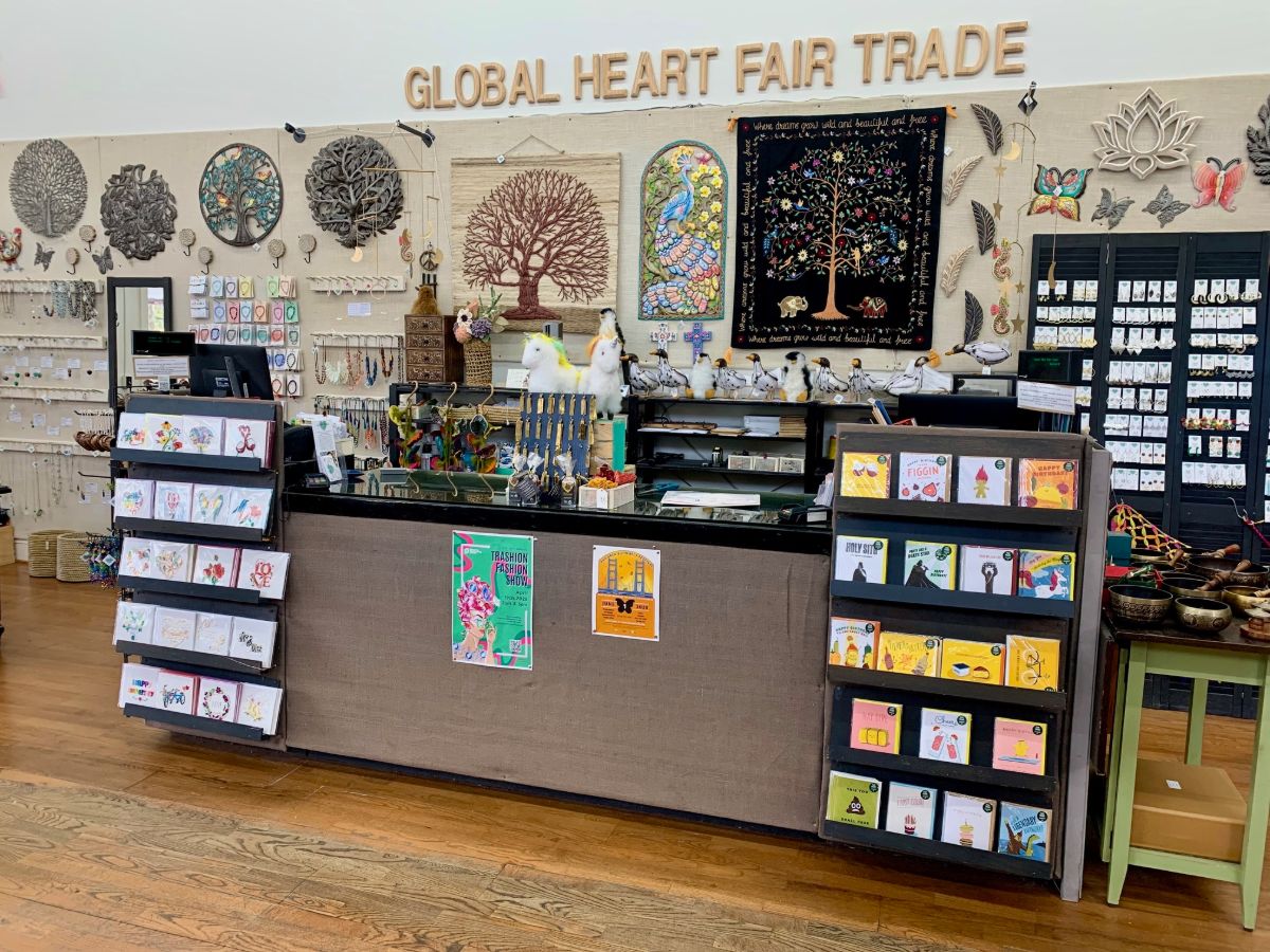 The front counter at Global Heart, with racks of cards and the shop name painted on the wall above